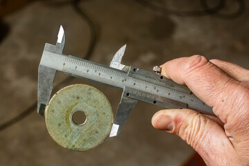Measuring the diameter of a metal washer using a caliper.