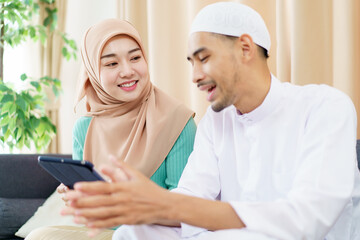 Good looking Asian muslim spouse reading and studying the Holy Koran together in living room.