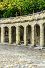 Obraz premium Stone Arches with Courtyard and Trees in Historic Setting