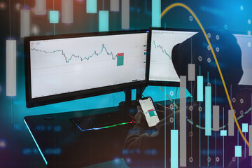 A man sitting in front of his computer, and he is trading.