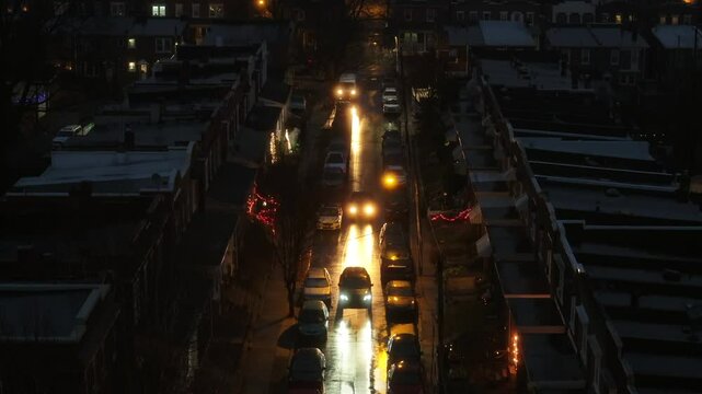 Urban city with traffic on dangerous street at night. Traffic and streetlights on main road. Aerial wide shot zoom. Row of low class housing area.