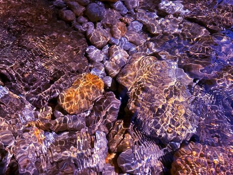 Sea stones pebbles with sun reflection on surface I