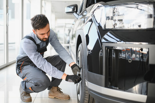 Car mechanic working in garage and changing wheel alloy tire. Repair or maintenance auto service. Replacement of winter and summer tires