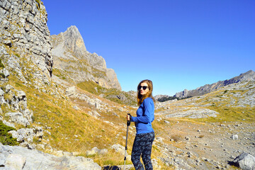 Hiking in scenic places: a female tourist in sportswear walks, using trekking poles, along a mountain valley towards the border of Albania and Montenegro (Buni i Jezerces, Prokletije National Park)