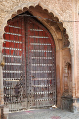 Old weathered red wooden door in the old town of Mathura, Uttar Pradesh, India, Asia