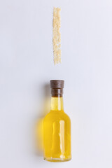 Sesame oil in glass bottle with seeds on white background