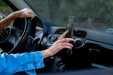 One hand on the wheel, the other reaching for the phone mounted on the support to check directions