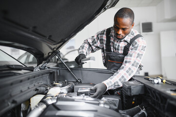 An African-American mechanic confidently posing with tools in hand in his workshop
