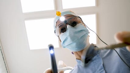 Female dentist wearing surgical mask performing detailed dental examination using specialized instruments during routine health checkup in slow motion