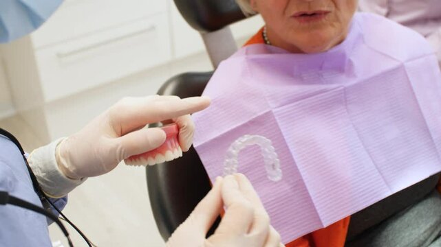 Professional dentist explaining invisible braces functionality using dental mold, highlighting orthodontic alignment technique in slow motion medical demonstration