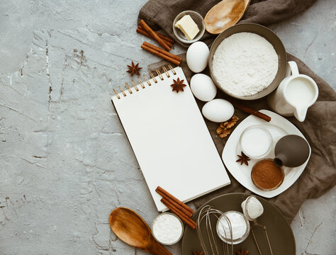 Overhead view of assorted baking ingredients and utensils on a table blank notepad