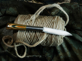 Vintage knife on rustic twine with camouflage background