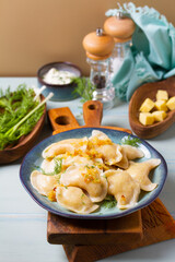 Dumplings with mashed potatoes filling. Varenyky, vareniki, pierogi, pyrohy - dumplings with filling on blue plate on green blue wood background