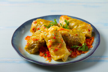 Stuffed cabbage leaves. Cabbage wraps or rolls. Chou farci, dolma, sarma, golubtsy or golabki on blue plate on green blue table