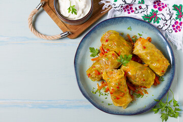 Stuffed cabbage leaves. Cabbage wraps or rolls. Chou farci, dolma, sarma, golubtsy or golabki on blue plate on green blue table. High angle view with copy space