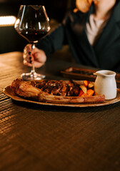 Delicious meat dish served with rich sauce and accompanied by a glass of red wine at an intimate dining setting
