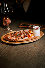Delicious meat dish with rich sauce served alongside a glass of red wine in an elegant dining setting