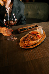 Delicious meat dish with sauce served on a wooden plate paired with a glass of red wine in a cozy dining setting
