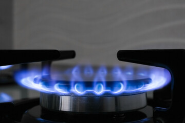 Gas burner of modern stove with burning blue flame, closeup