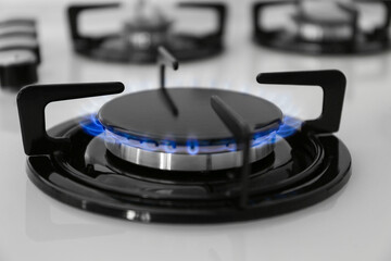 Gas burner of modern stove with burning blue flame, closeup