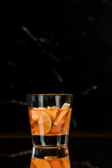 whiskey in a glass with ice and lime on a black mirror background, place for drinks, alcohol, alcoholic cocktails, exquisite whiskey cocktail