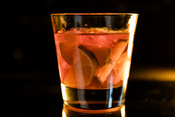 whiskey in a glass with ice and lime on a black mirror background, place for drinks, alcohol, alcoholic cocktails, exquisite whiskey cocktail