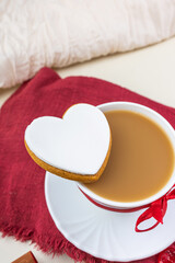 cappuccino in a large white cup with a red ribbon, gingerbread cookies with white glaze, red...