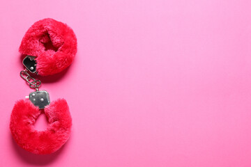 Fluffy handcuffs on pink background, top view. Space for text