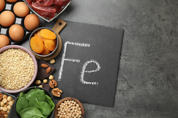 Diet plan for anemia. Different products rich in iron and slate board with Ferrum symbol on grey table, flat lay. Space for text © New Africa