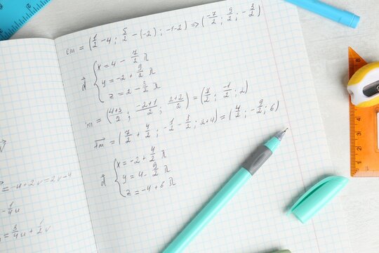 Doing homework. Notebook with math assignment and stationery on white desk, flat lay