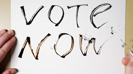 Handwriting vote now in bold letters on white paper with emphasis on active participation. - Powered by Adobe