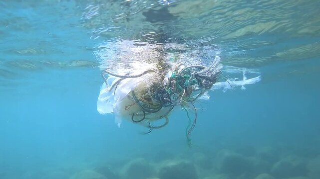 A tangled mass of fishing nets and plastic floats just beneath the ocean&rsquo;s surface, highlighting the ongoing issue of marine pollution threatening aquatic ecosystems.