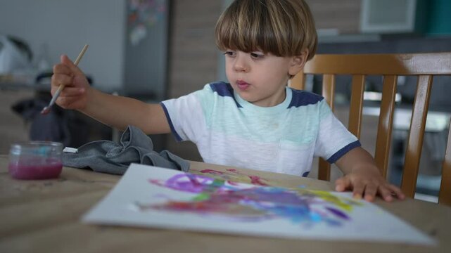 One small boy painting with water paint and brush. creative child plays with abtract aquarelle watercolor at home