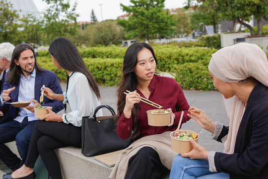 Group of multiracial business people eating together outside of office at city park - Healthy food and entrepreneur concept