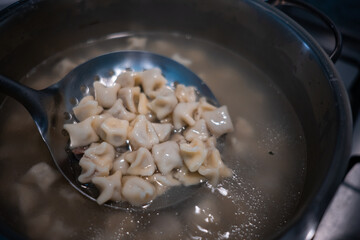 Traditional Turkish dish manti is being boiled in a pot.