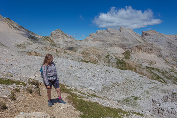 Young woman with long hair looking at the awesome summer valley panorama in the Dolomites, Mount Latemar, Trentino, Italy. Traveling photography and outdoor sport activity concept