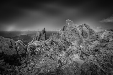Black and white image of Trekkers along path in a awesome summer dolomite rocky scenario in the Latemar Massif, UNESCO world heritage site. Trentino-Alto Adige, Italy, Europe