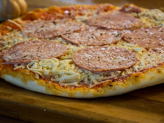Frozen pizza. Delicious salami pizza with cheese on a wooden board.