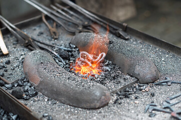 Blacksmith's forge with tools, glowing metal, and a burning flame in a traditional workshop.