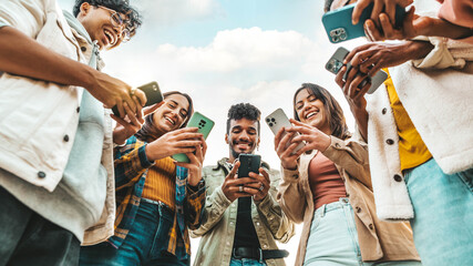 Obraz premium Teens in circle holding smart mobile phones - Multicultural young people using cellphones outside - Teenagers addicted to new technology concept