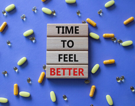 Time to feel better symbol. Concept word Time to feel better on wooden blocks. Beautiful purple background with pills. Health concept. Copy space