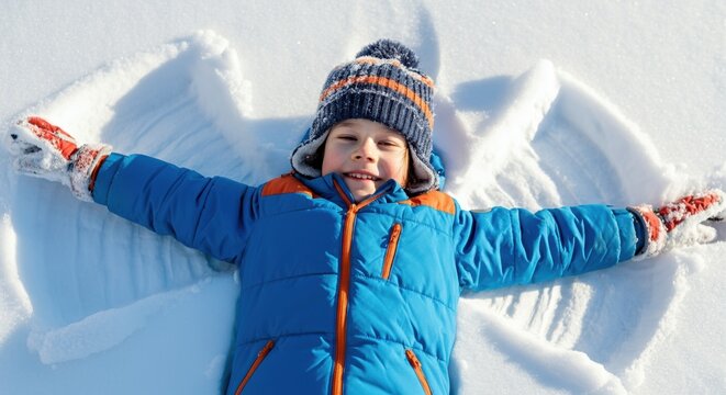 Happy boy making snow angel in fresh winter snow