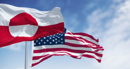 Flags of Greenland and the US waving in the wind on a clear day