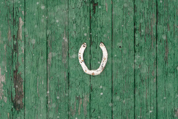 A green wooden door with a white horseshoe on it