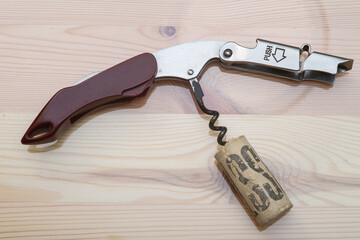 Manual corkscrew with the auger screw stuck inside a cork stopper after uncorking a bottle of wine