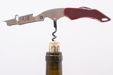 manual corkscrew inserted into a cork stopper in the neck of a wine bottle