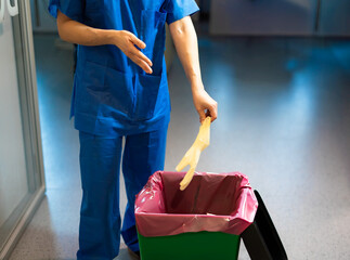 hospital nurse disposing of used gloves in biological container
