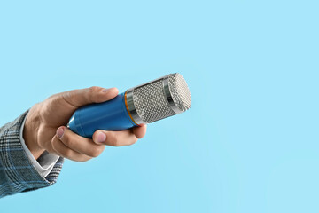 Man with microphone on light blue background, closeup