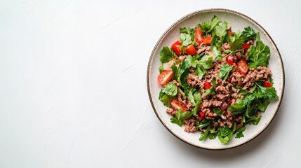 Plate of spicy Thai larb minced meat salad garnished with fresh herbs on a white background