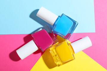 Bright nail polishes in bottles on color background, flat lay